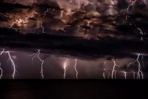 Powerful thunderstorm with dark clouds and visible lightning bolts, illustrating the danger of severe weather.