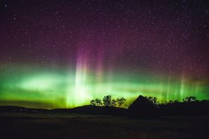 Vivid northern lights glowing across a night sky, a visible effect of geomagnetic storms caused by solar activity.